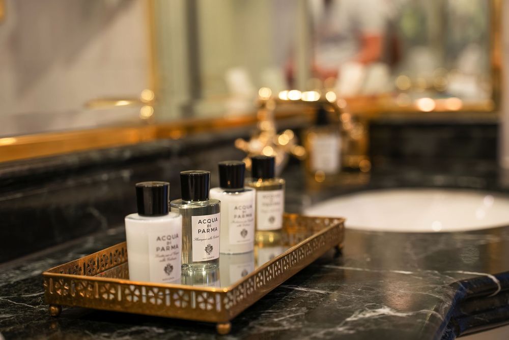 Un comptoir de salle de bains avec un plateau décoratif tenant plusieurs petites bouteilles de…