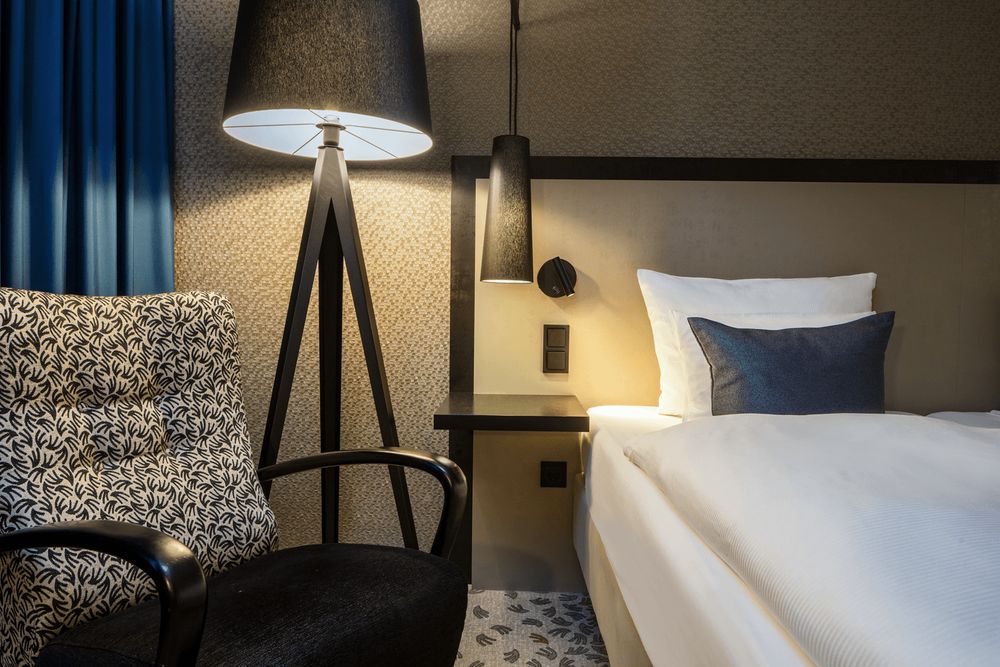 Een slaapkamerhoek met een bed, een stoel en een vloerlamp.