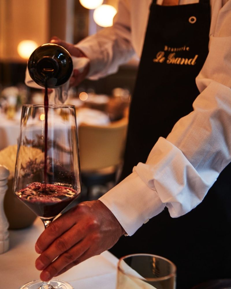 A person is pouring red wine into a wine glass.