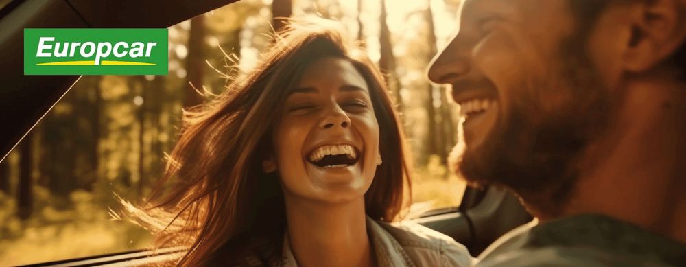 Ein Mann und eine Frau genießen gemeinsam fröhlich eine Autofahrt, mit dem Europcar-Logo angezeigt.