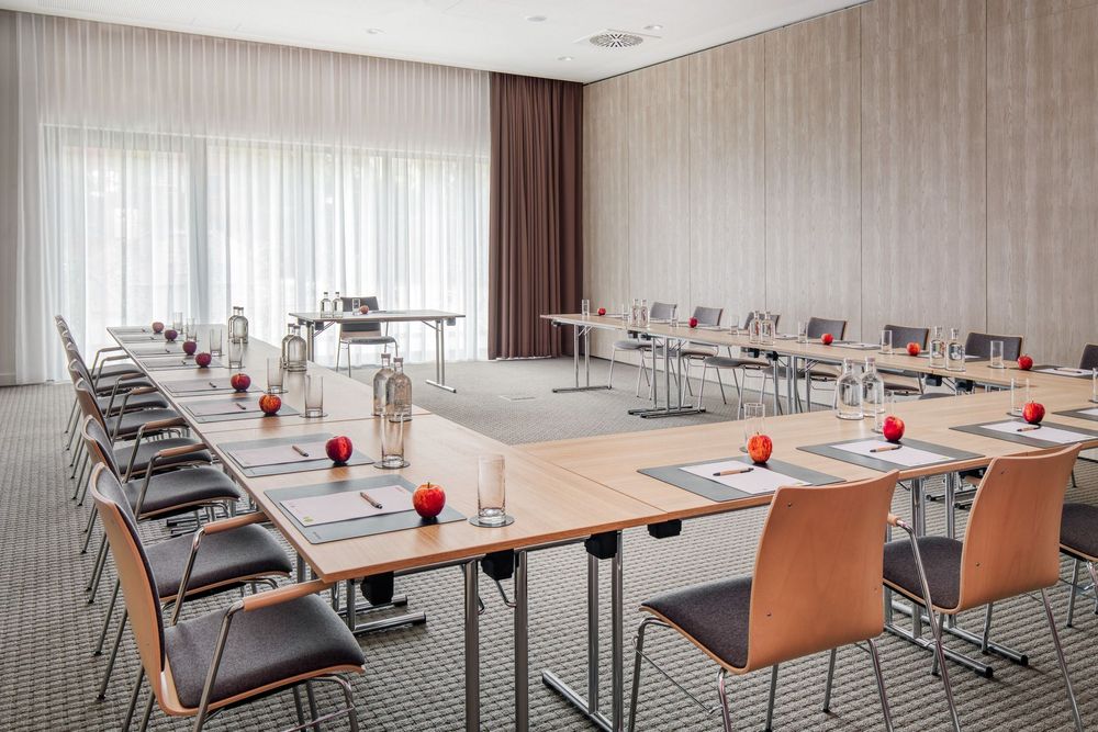 A conference room set up with tables and chairs arranged in a U-shape for a meeting or presentation.