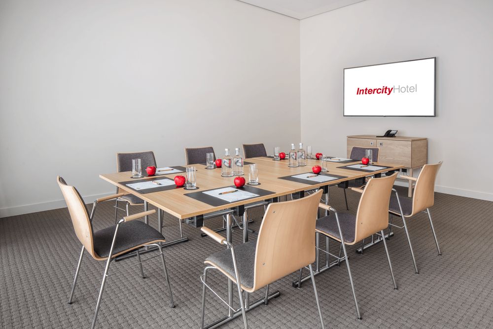 A small conference room with a table, chairs, and a screen displaying the Intercity Hotel logo.