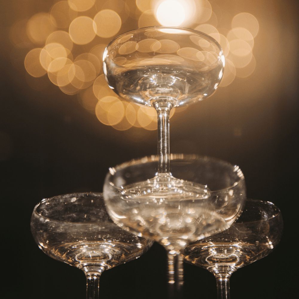 Een close-up van opgestapelde lege wijn- of champagneglazen met wazige lichten op de achtergrond.