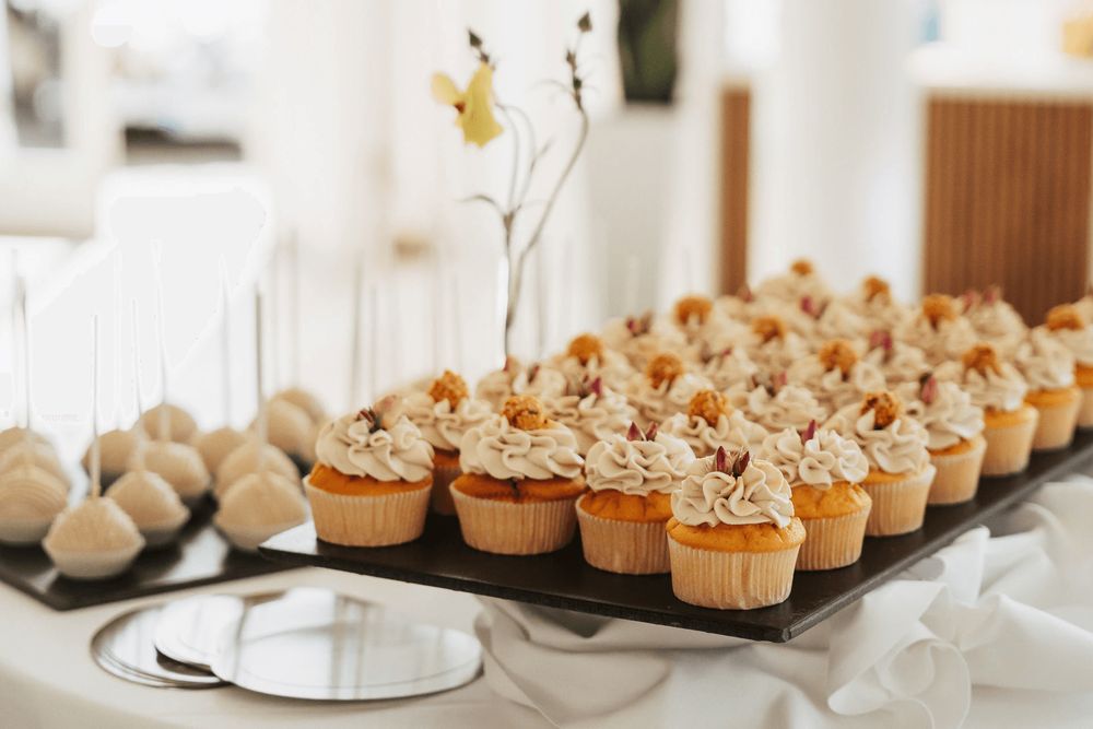 Ein Tablett mit Cupcakes mit Zuckerguss ist auf einem Tisch präsentiert.