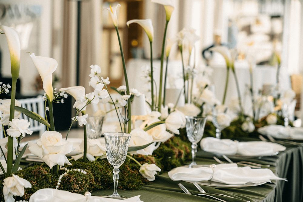 Ein festlich gedeckter Esstisch mit weißen Blumen und Glasgeschirr.
