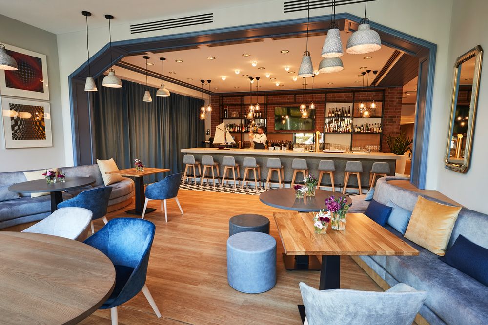 Das Foto zeigt eine moderne Bar mit Sitzgelegenheiten, darunter Stühle, Hocker und Tische.