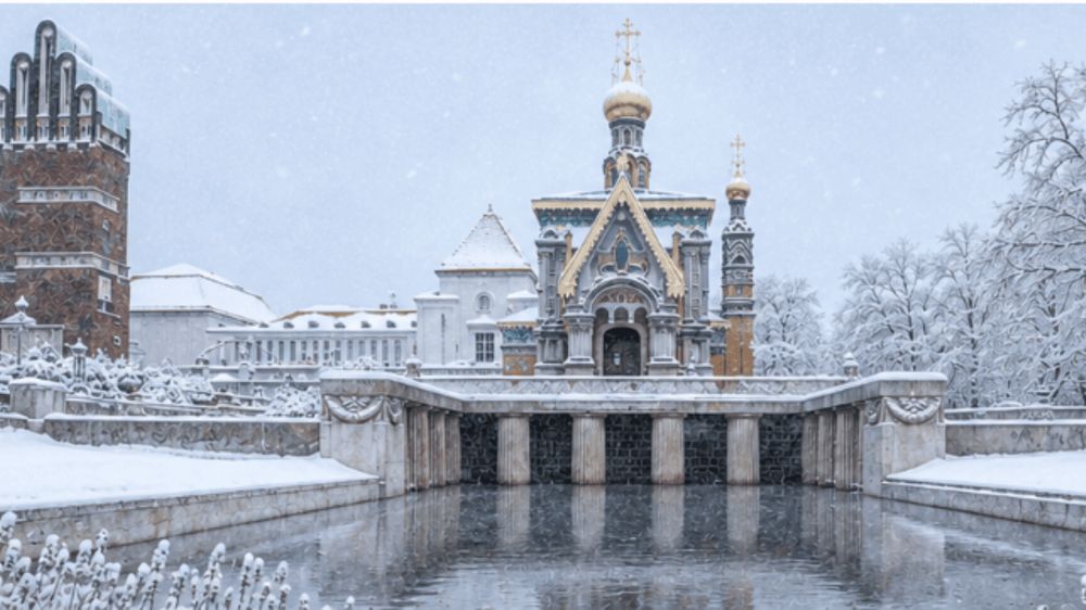 Ein historisches Gebäude mit einem Gewässer davor, umgeben von schneebedeckten Bäumen und Boden.