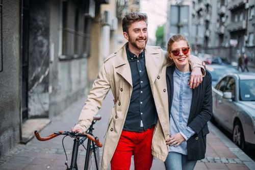 Un homme et une femme marchant dehors, l'homme tenant un vélo et la femme portant des lunettes de…