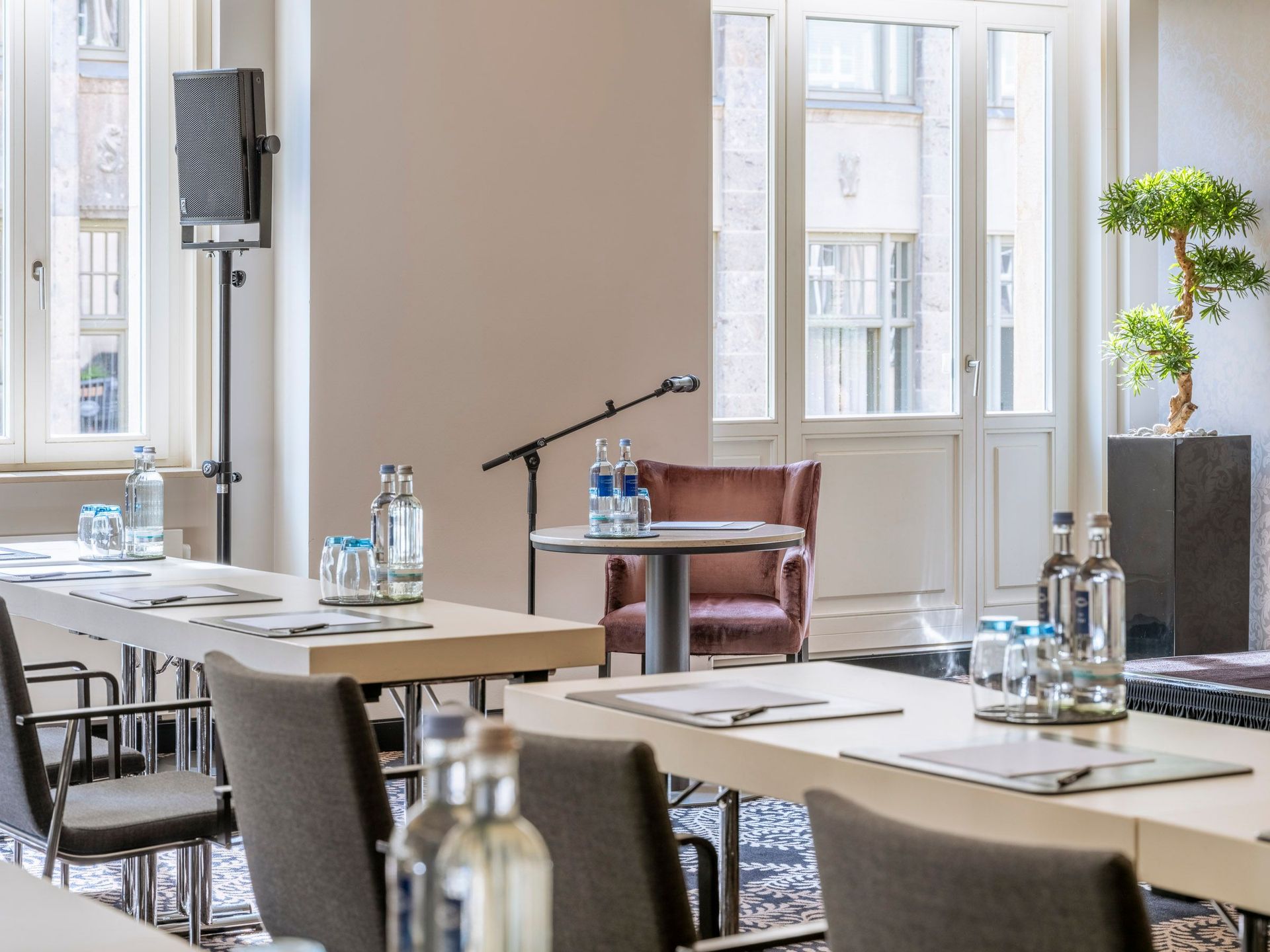 Ein moderner Konferenzraum mit Stühlen, Tischen, Wasserflaschen und einem Mikrofon neben einem…