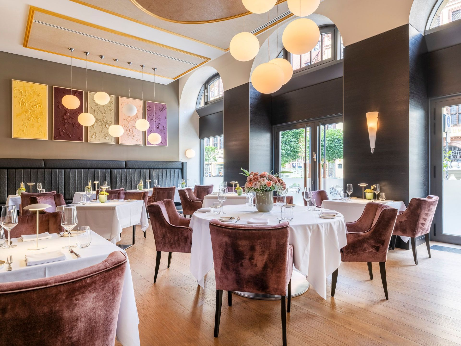 Ein moderner Restaurant-Speiseraum mit runden und quadratischen Tischen, gepolsterten Stühlen und…