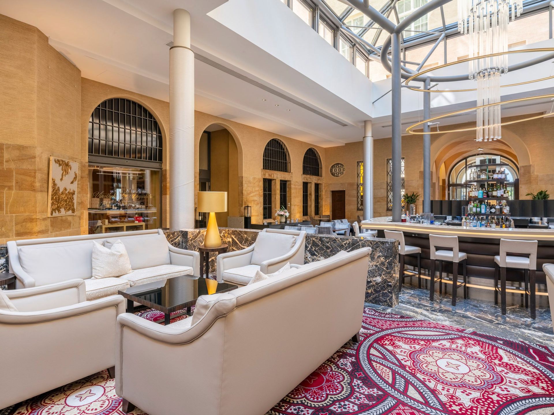 Das Foto zeigt einen gut beleuchteten, eleganten Loungebereich mit bequemen Sofas, einer Bar und…
