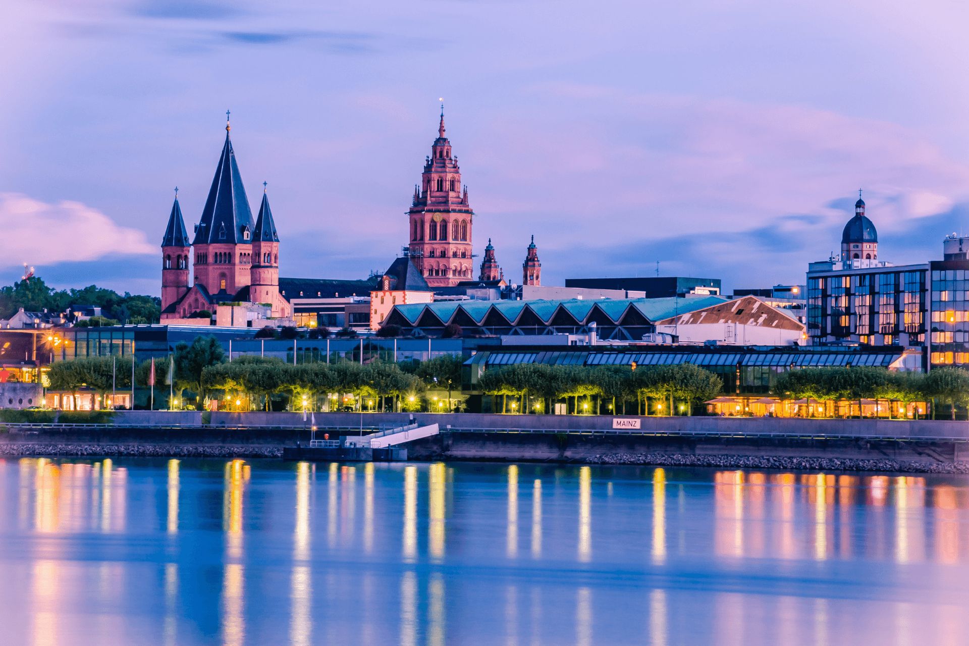 A cityscape at dusk featuring historic buildings and their reflections in a body of water.