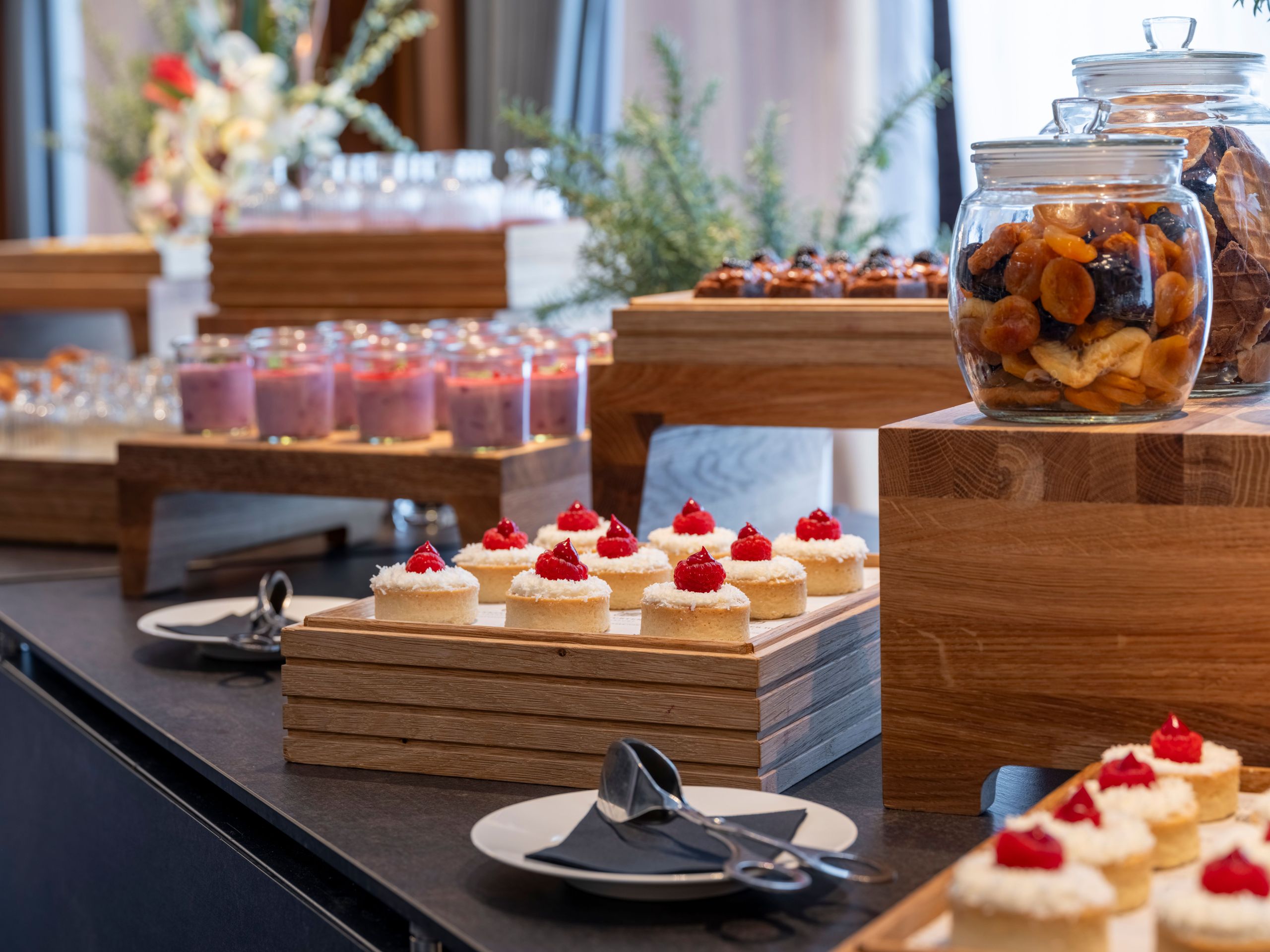 Ein Dessertbüfett mit verschiedenen Süßigkeiten, darunter Kuchen und Gläser mit Trockenfrüchten,…