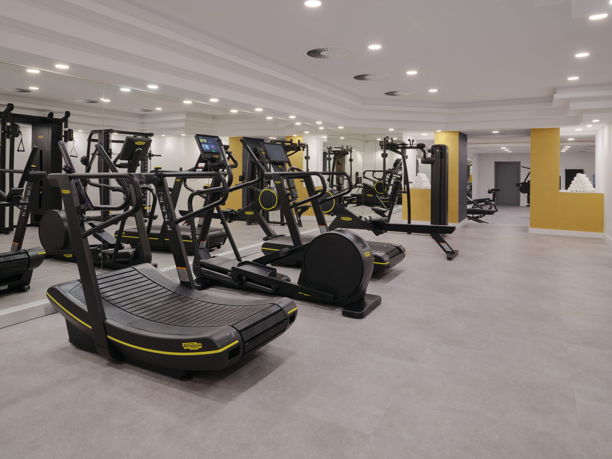 Das Foto zeigt ein geräumiges Fitnessstudio mit verschiedenen Trainingsgeräten.