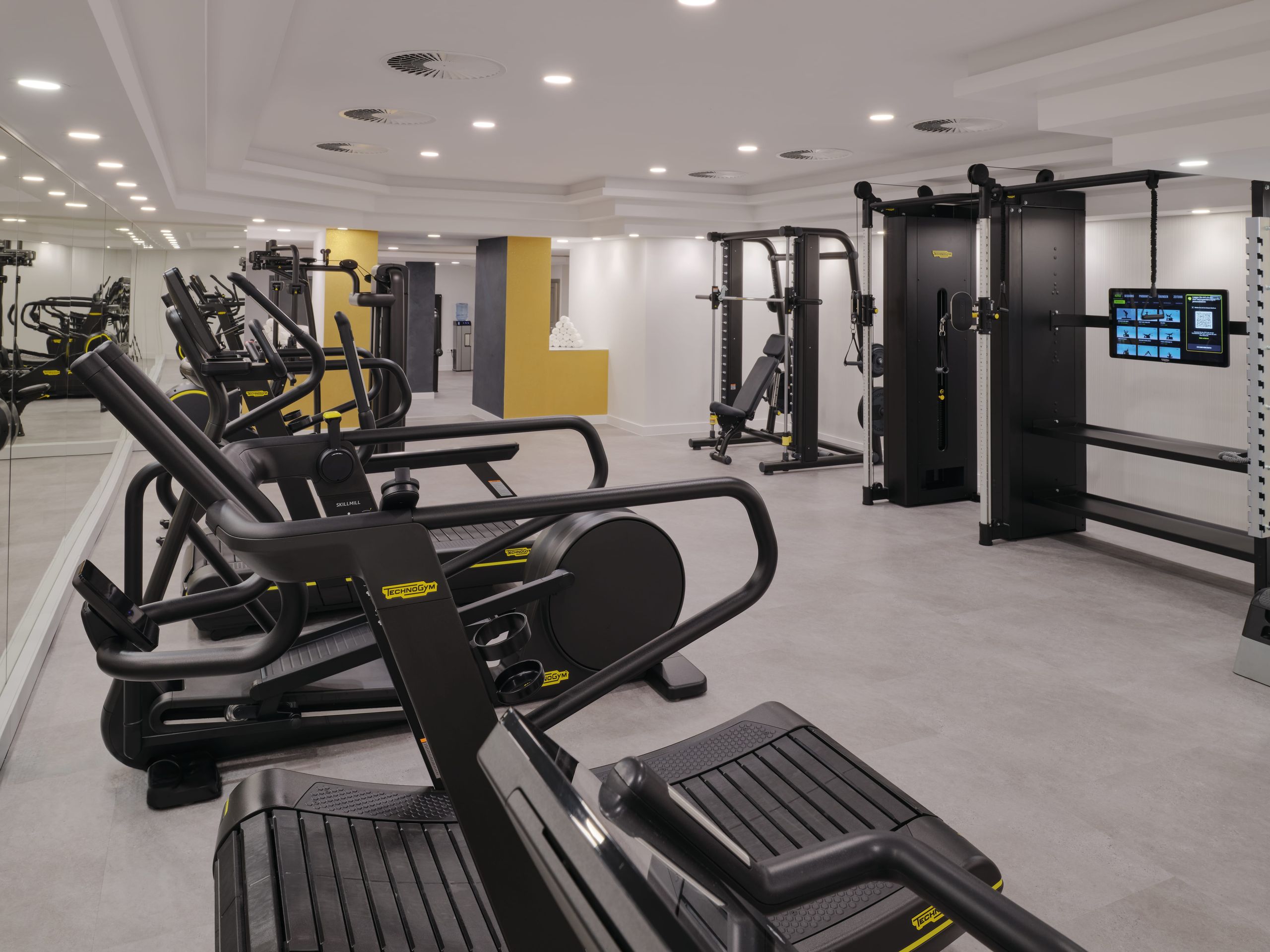Das Foto zeigt das Innere eines modernen Fitnessstudios mit verschiedenen Trainingsgeräten.