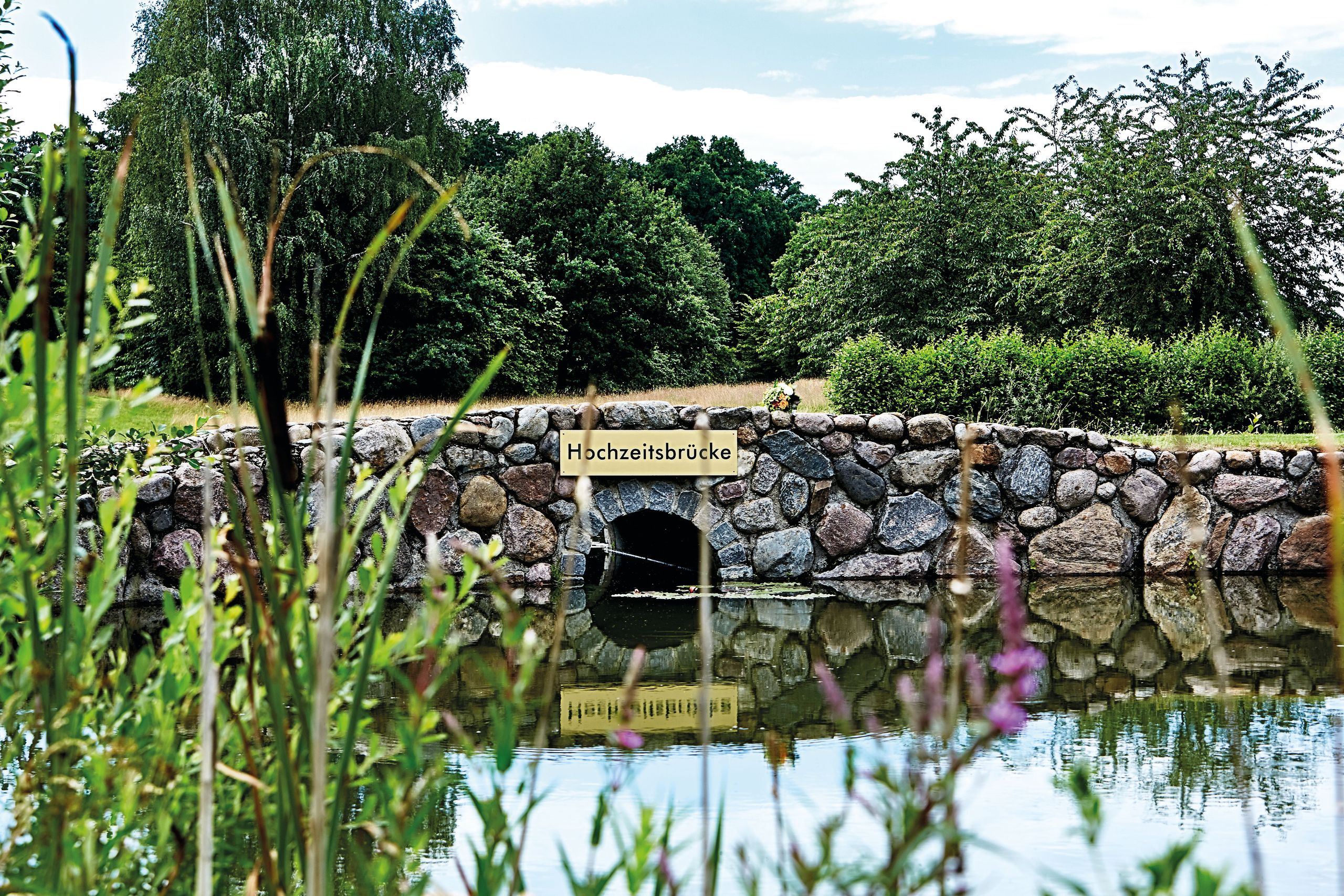 Un pont en pierre au-dessus d'un plan d'eau calme dans un cadre naturel verdoyant.