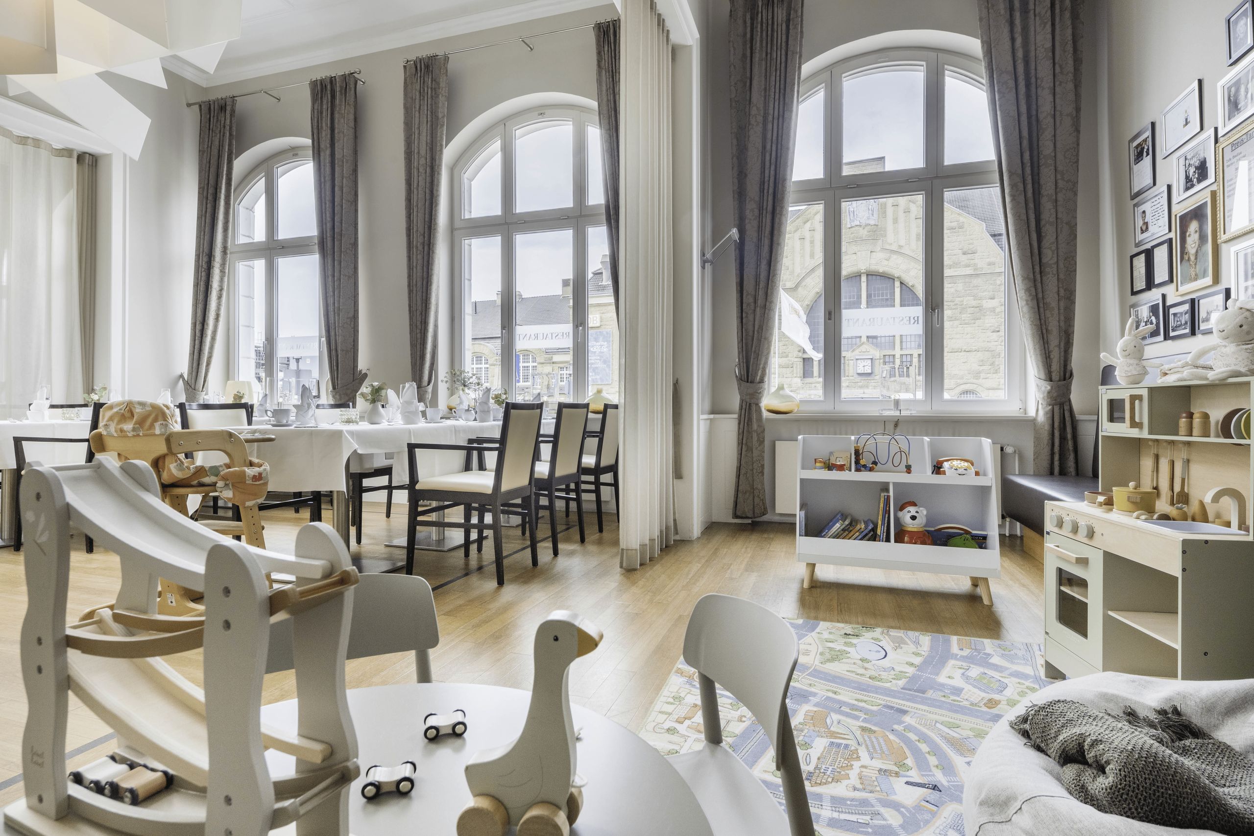 A bright and spacious room combining a dining area with tables and chairs and a play area with…
