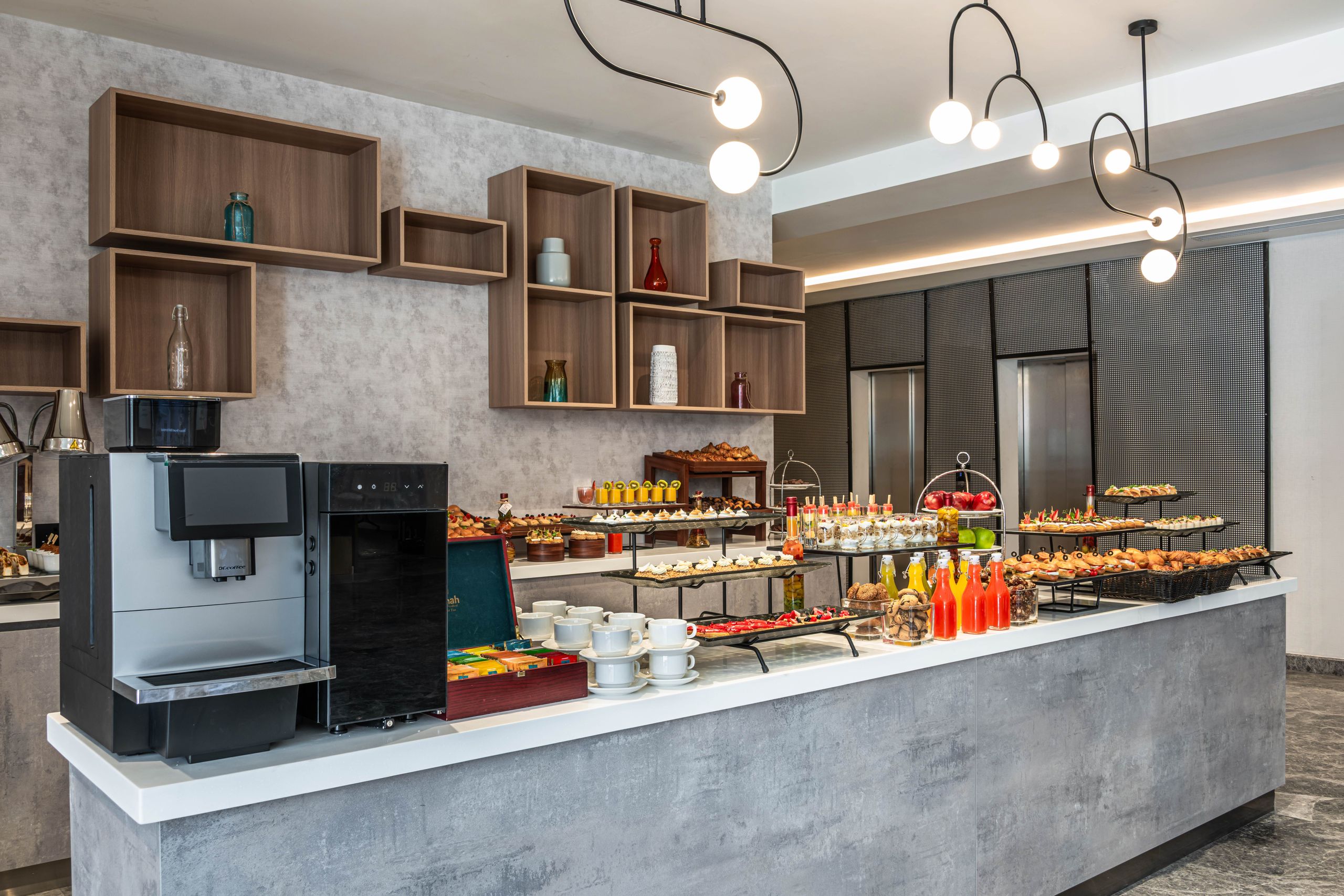 A modern buffet setup with a variety of food and beverages displayed on a counter in a…
