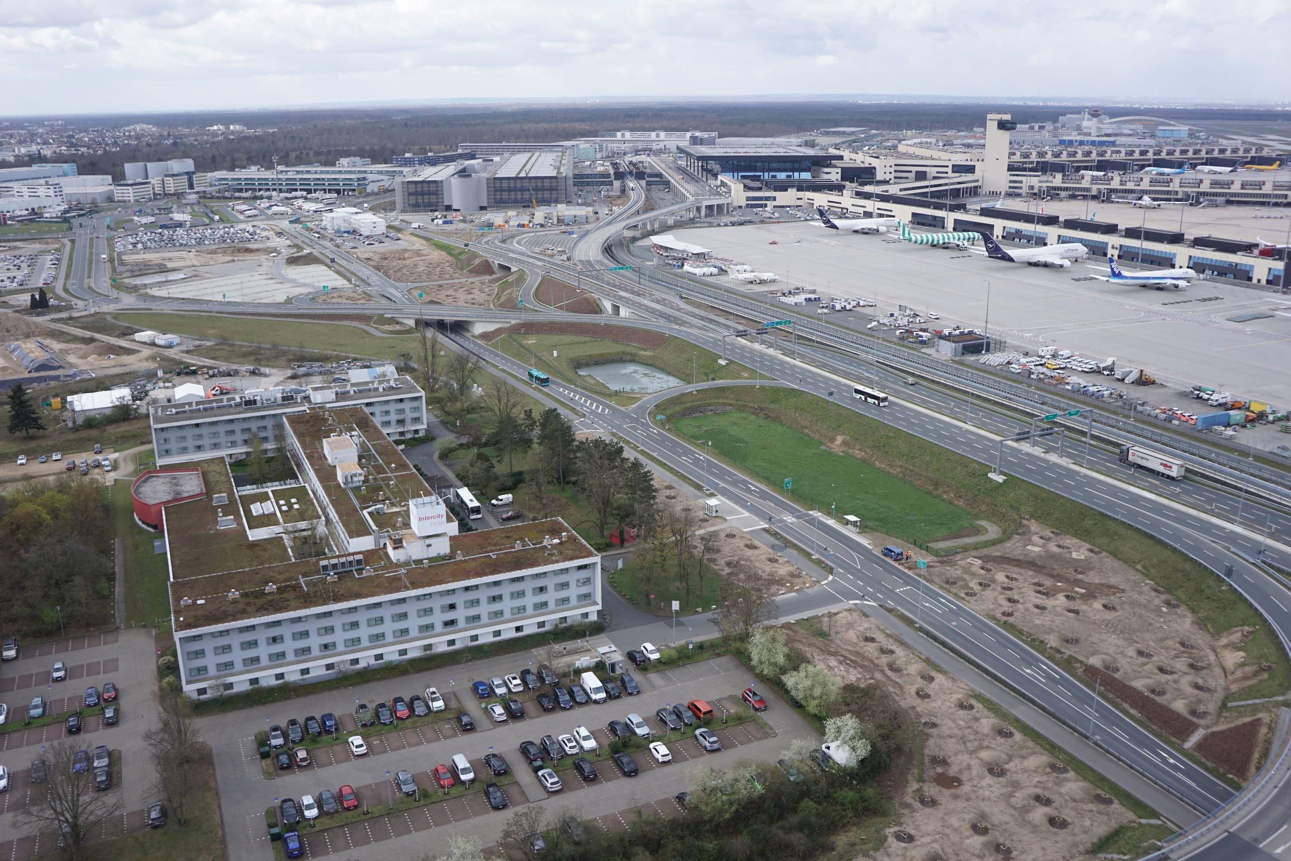 The photo shows an aerial view of an airport with multiple airplanes on the tarmac, surrounding…