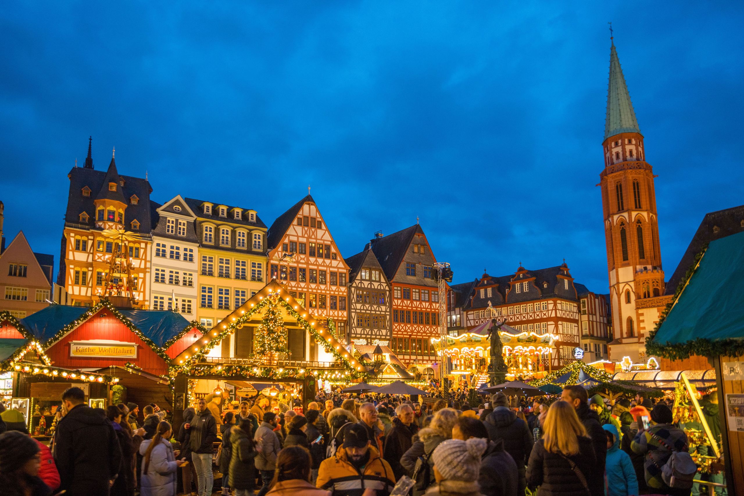 Ein überfüllter Weihnachtsmarkt auf einem historischen Marktplatz mit traditionellen…