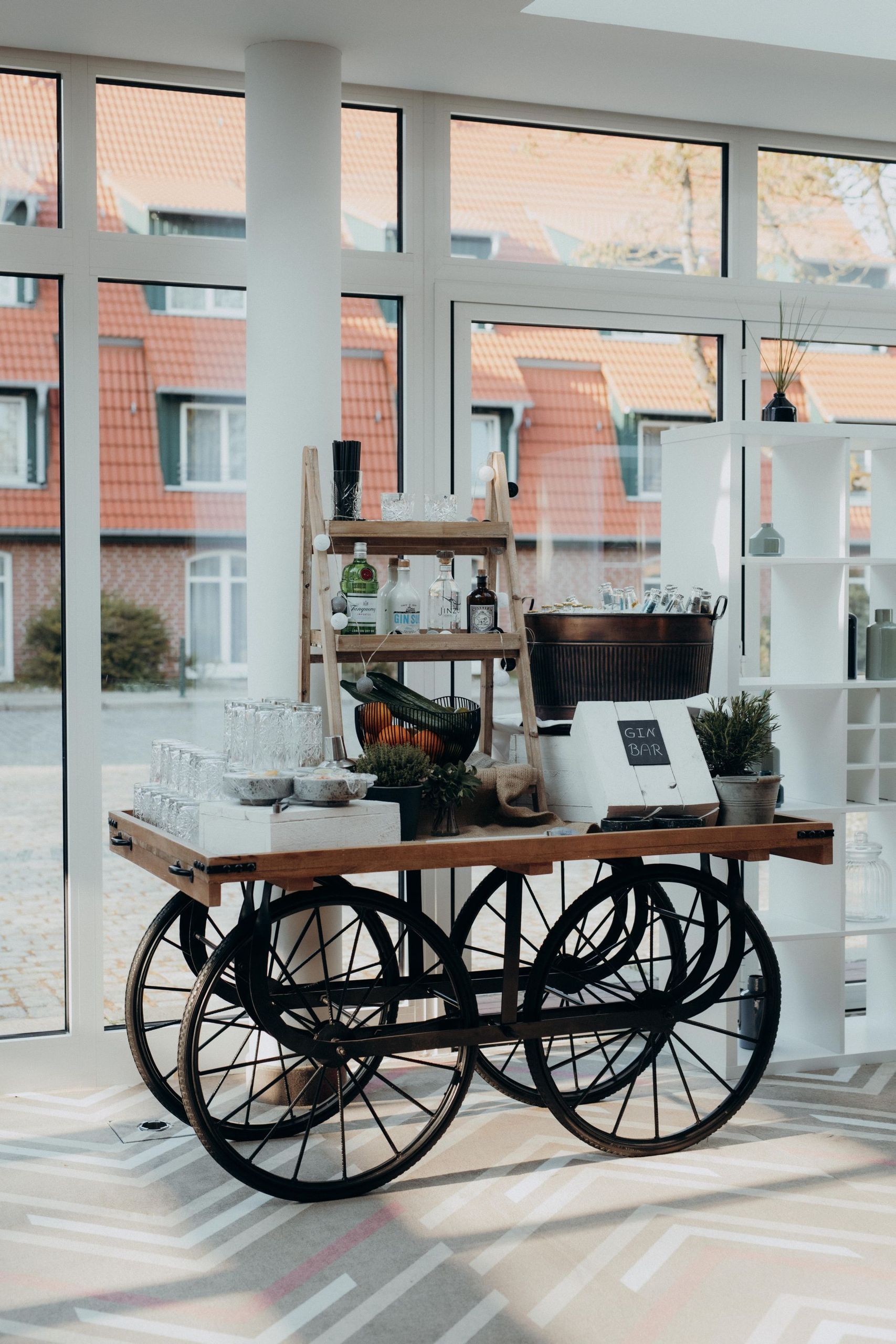 Un chariot en bois avec de grandes roues est installé à l'intérieur près de grandes fenêtres,…