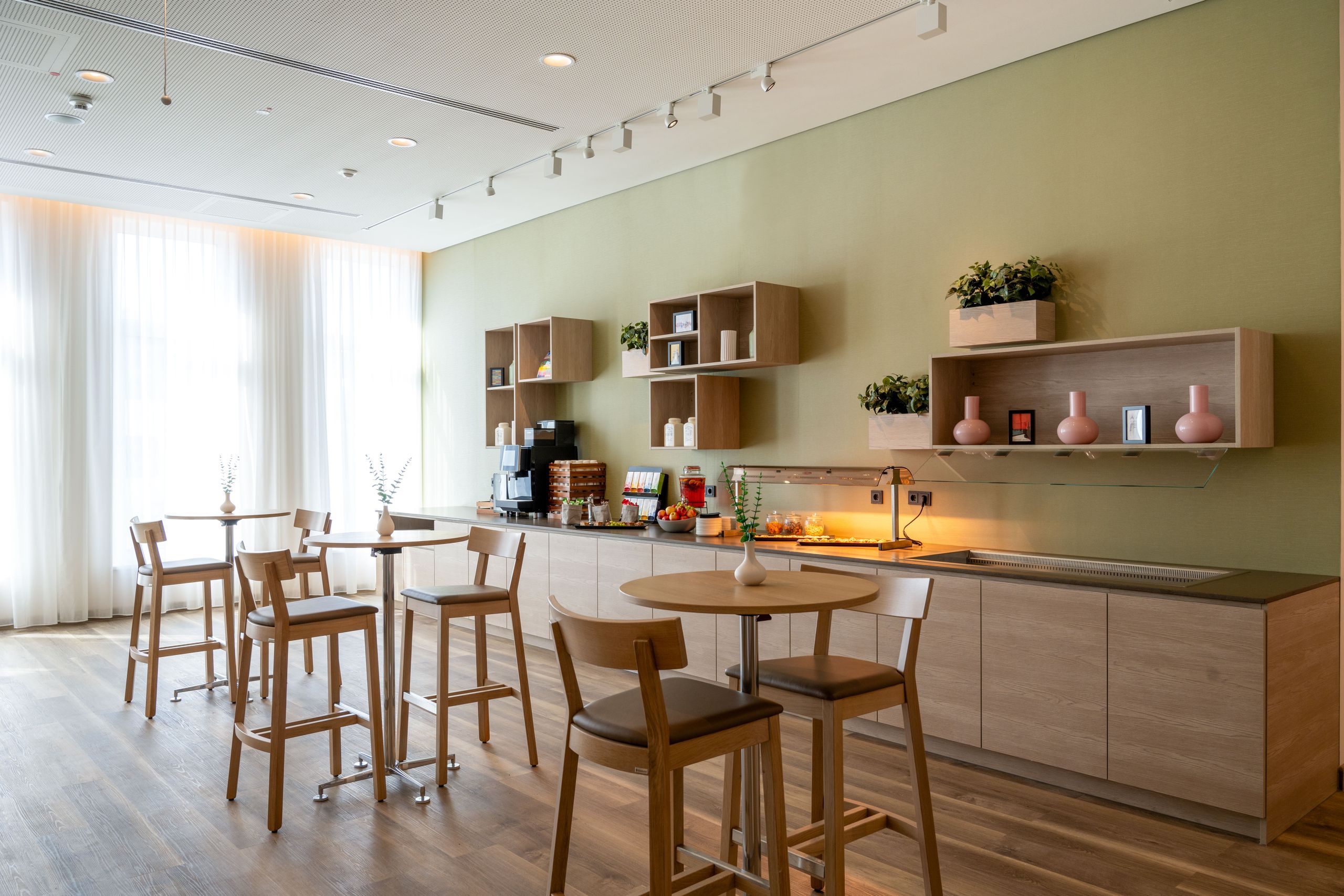 The photo shows a modern, minimalist dining area with tables and chairs, cabinetry, and shelves…