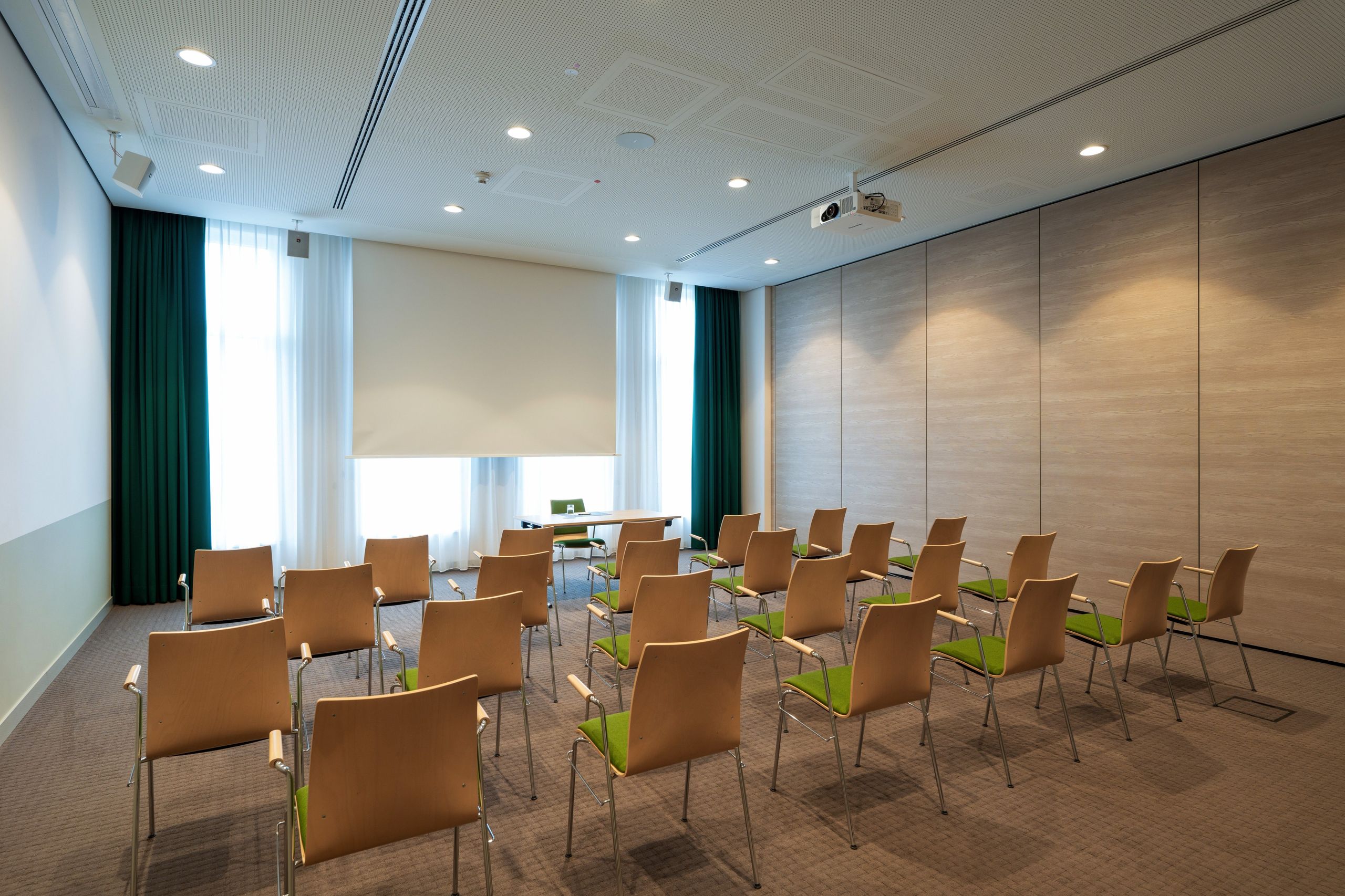Ein kleiner Konferenz- oder Besprechungsraum mit Reihen von Stühlen, die auf eine Leinwand oder…