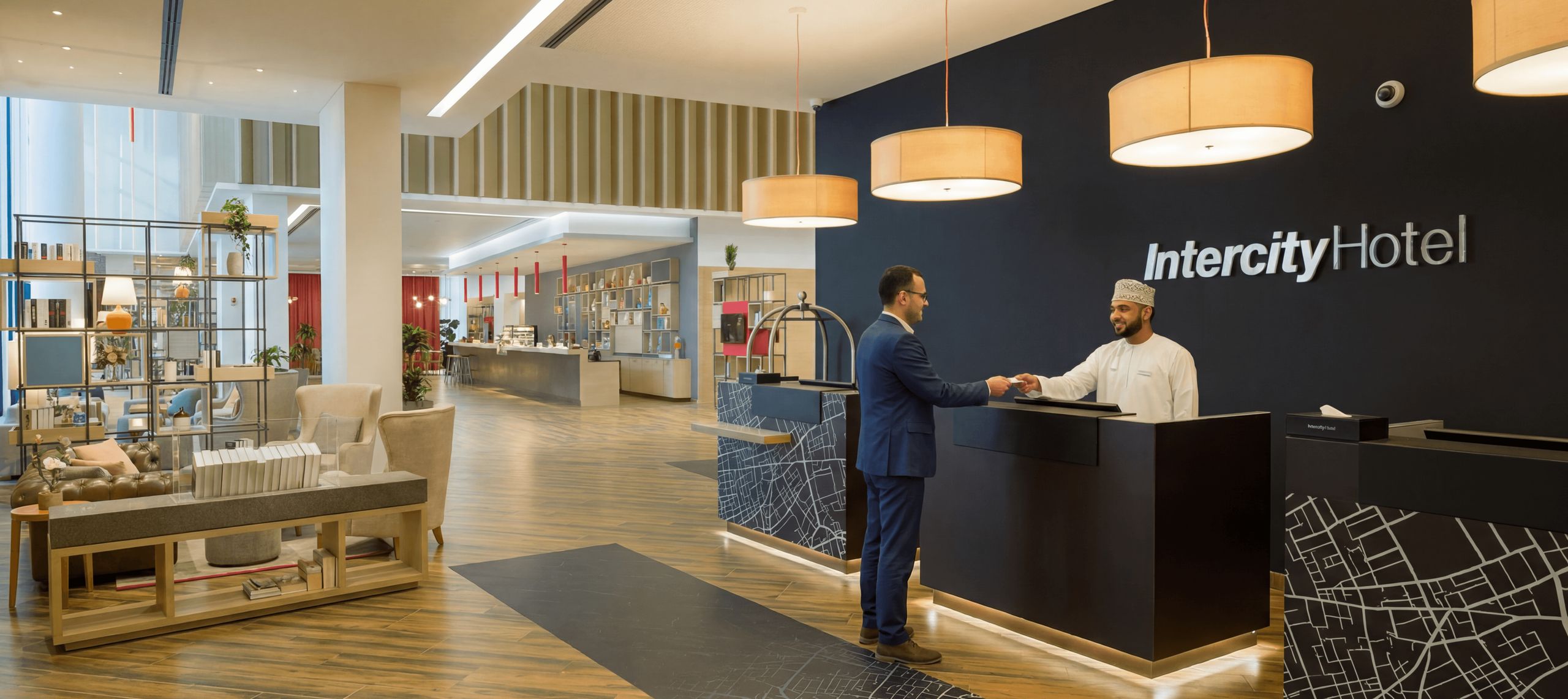 De foto toont de ruime lobby van een modern hotel met een receptiebalie en zitgedeelte.