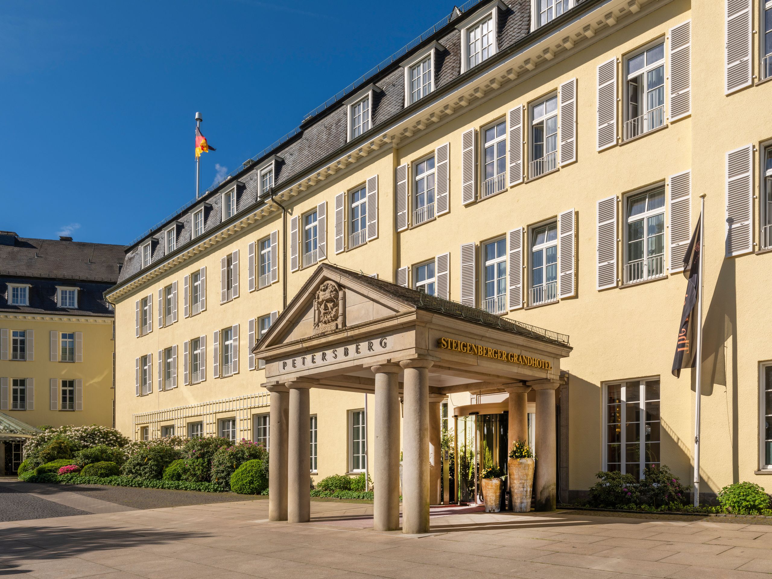 Un grand bâtiment de style classique avec une entrée à colonnes et un drapeau sur le toit.