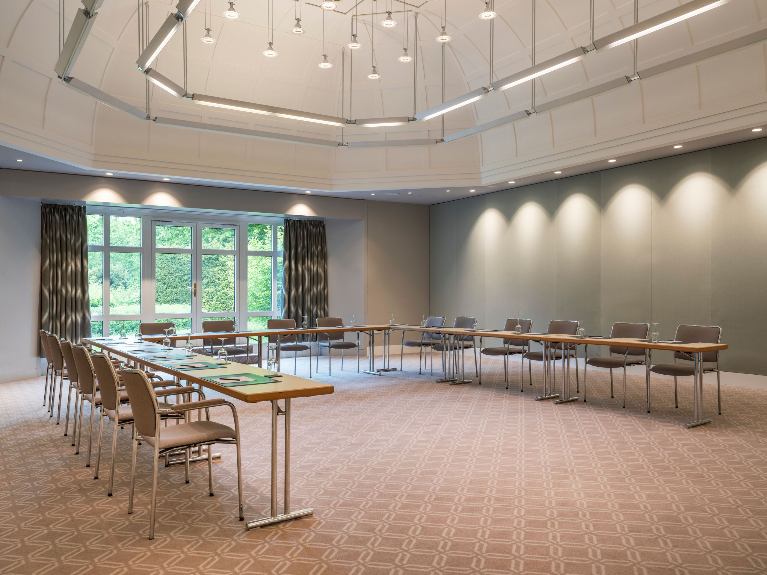 Ein geräumiger Konferenzraum mit Tischen in U-Form angeordnet und Stühlen darum.