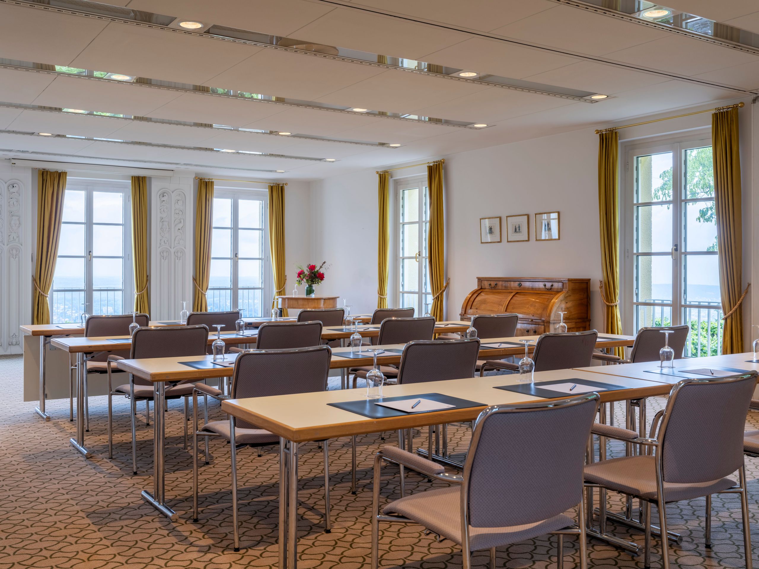 Ein Klassenzimmer- oder Konferenzraum mit Tischen und Stühlen, die in Reihen zum Vordergrund…