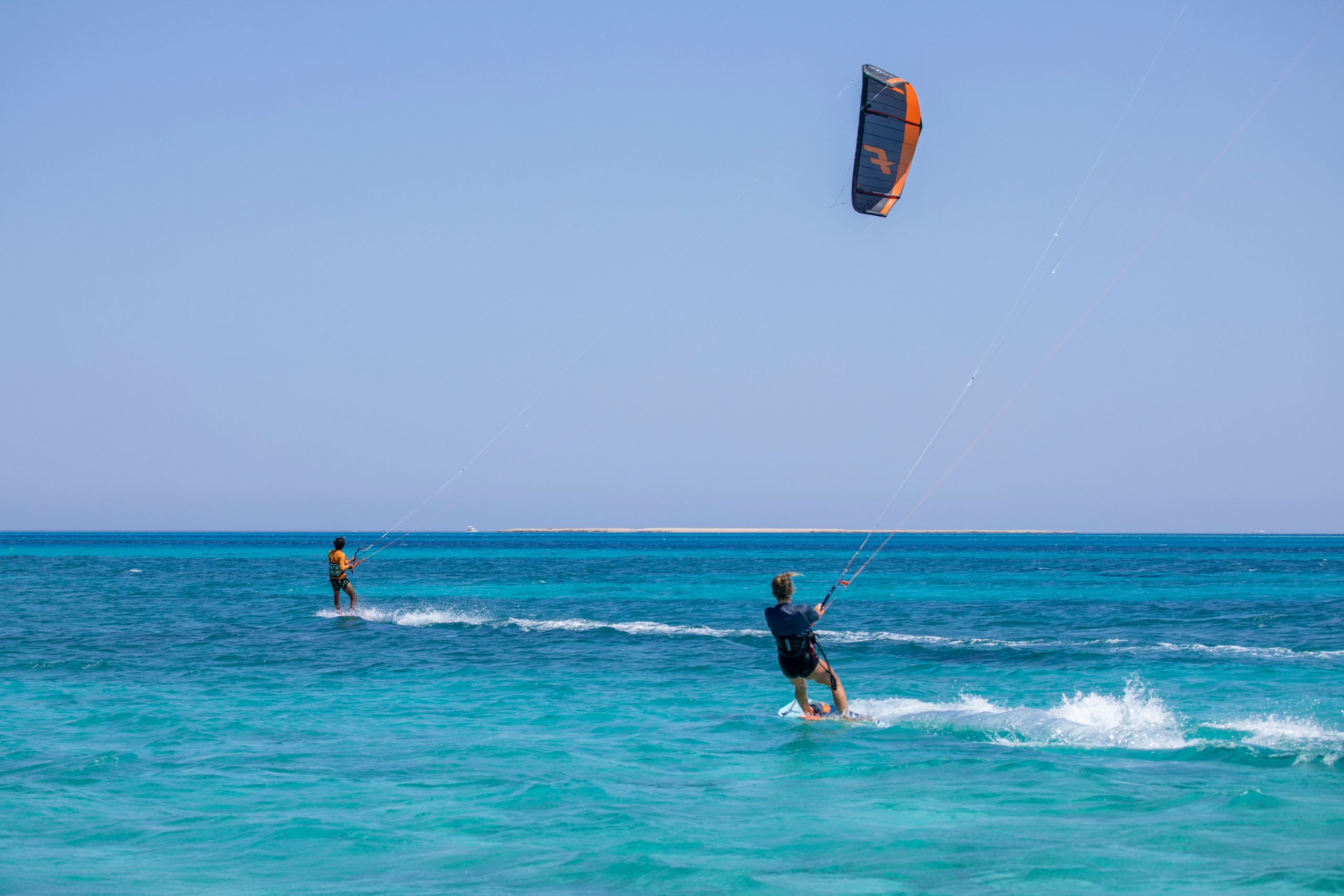 Два человека занимаются кайтбордингом на океане.