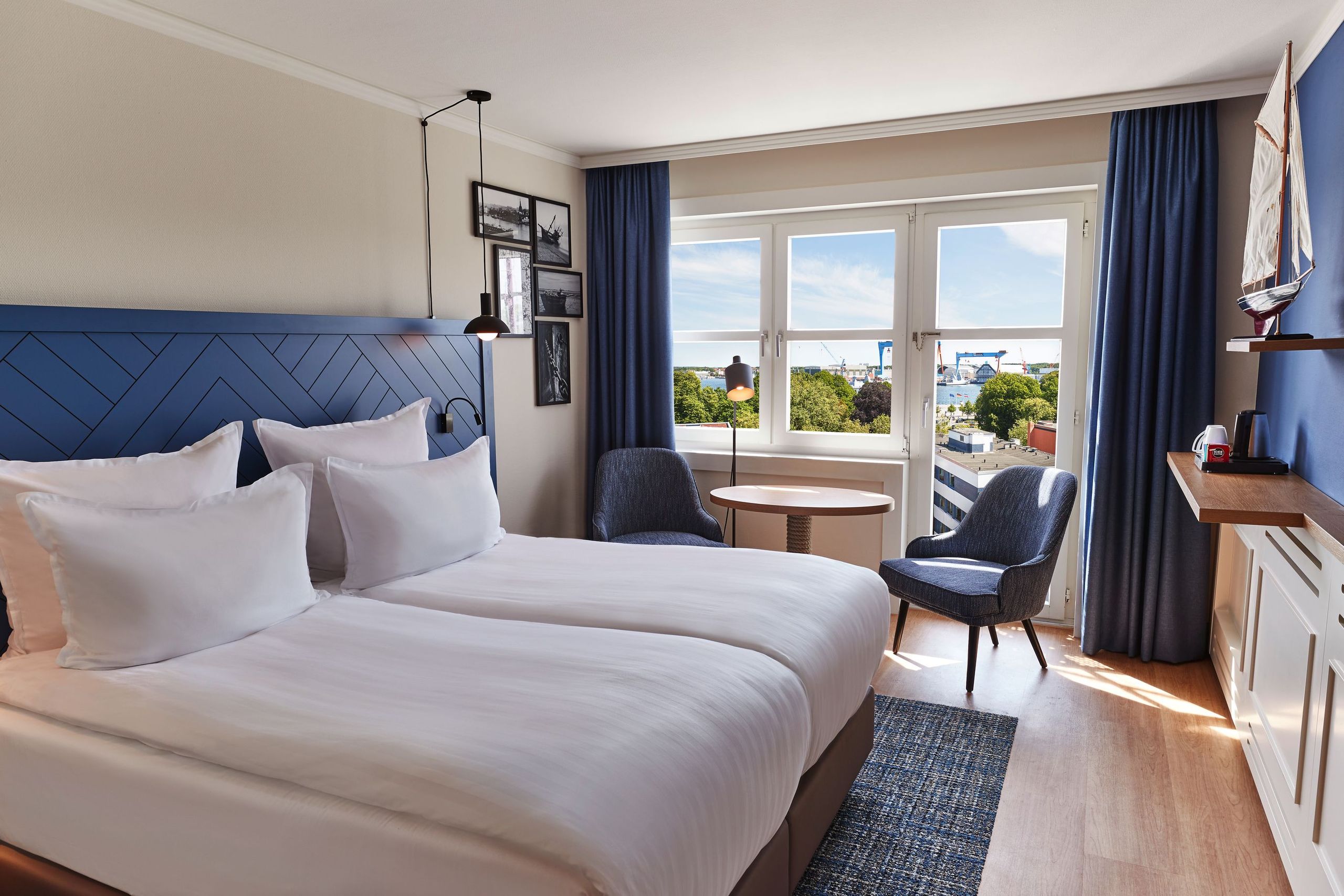 Una habitación de hotel moderna con una cama doble, dos sillas, una pequeña mesa redonda y una…