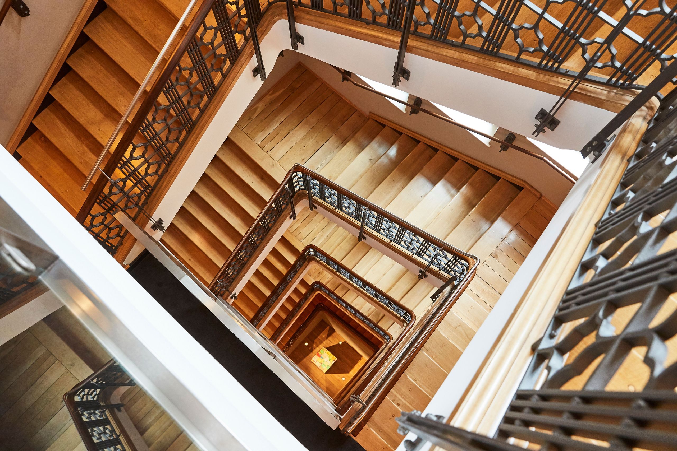 Ein Blick nach unten auf eine Wendeltreppe mit Holzstufen und Metallgeländern.