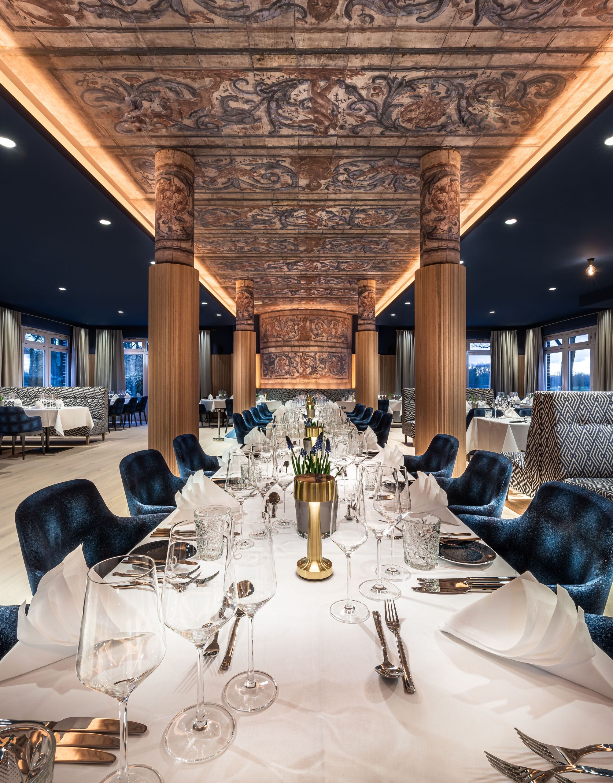 La photo montre une table à manger élégamment dressée dans un intérieur de restaurant luxueux avec…