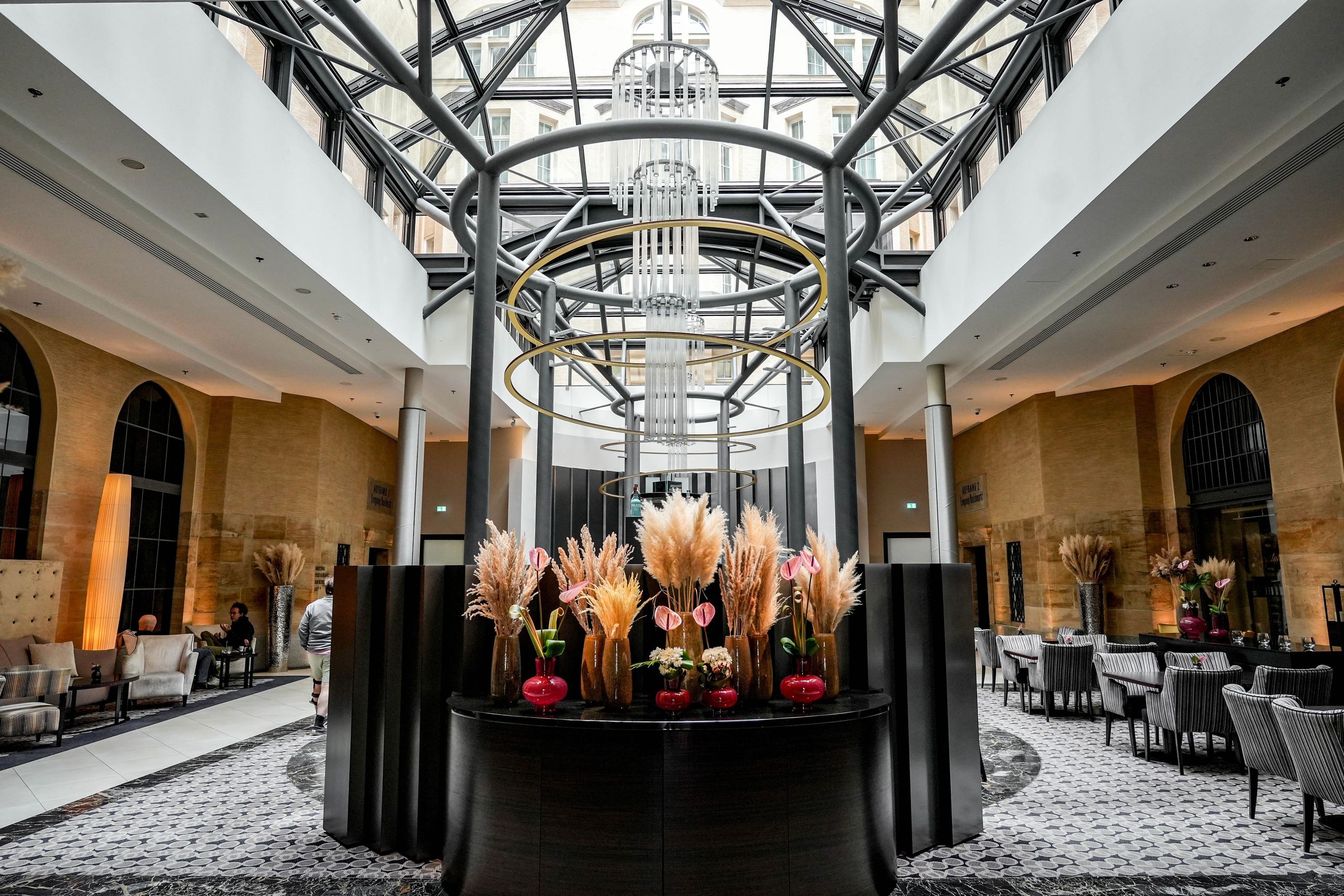An interior view of a spacious, modern lobby or lounge with seating areas and decorative plants in…