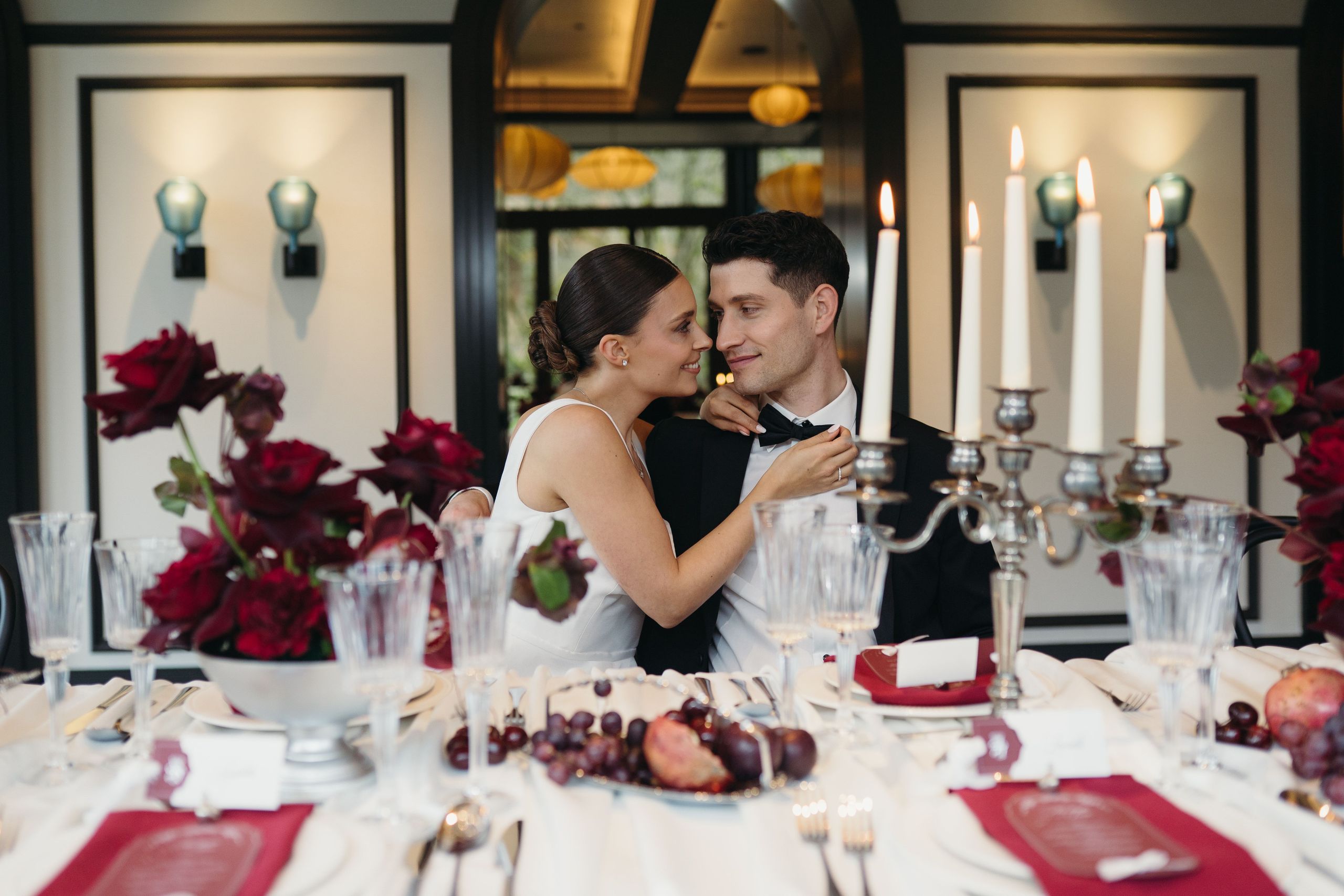 Пара обнимается и смотрит друг на друга с любовью за красиво накрытым столом.