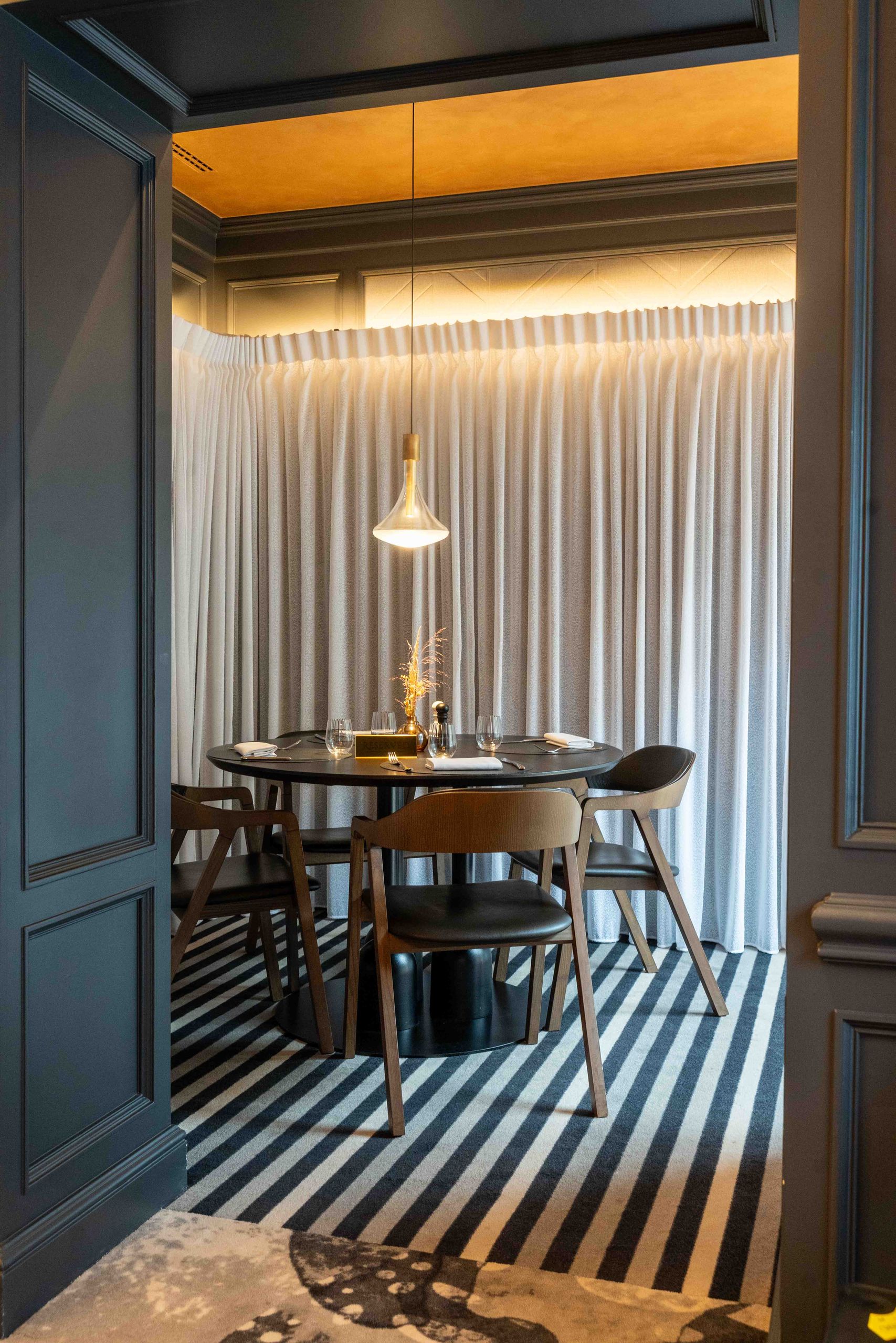 Une salle à manger moderne avec une table ronde, plusieurs chaises, une suspension lumineuse et un…