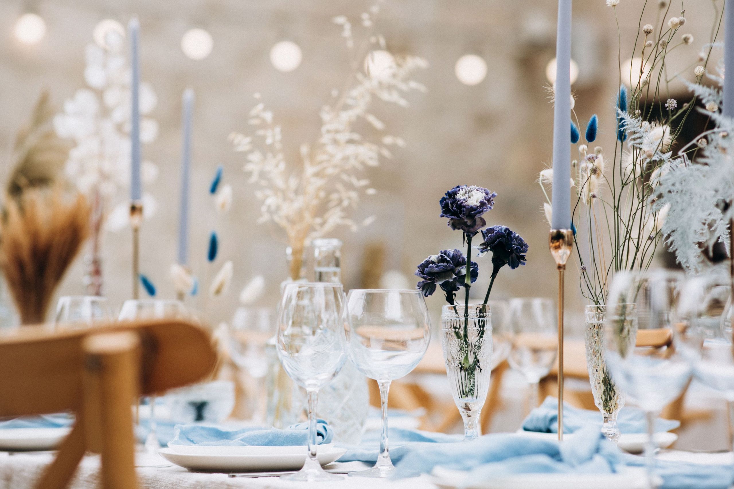 طاولة معدة لمناسبة خاصة مع أوانٍ زجاجية وأطباق وشموع وترتيبات زهور.