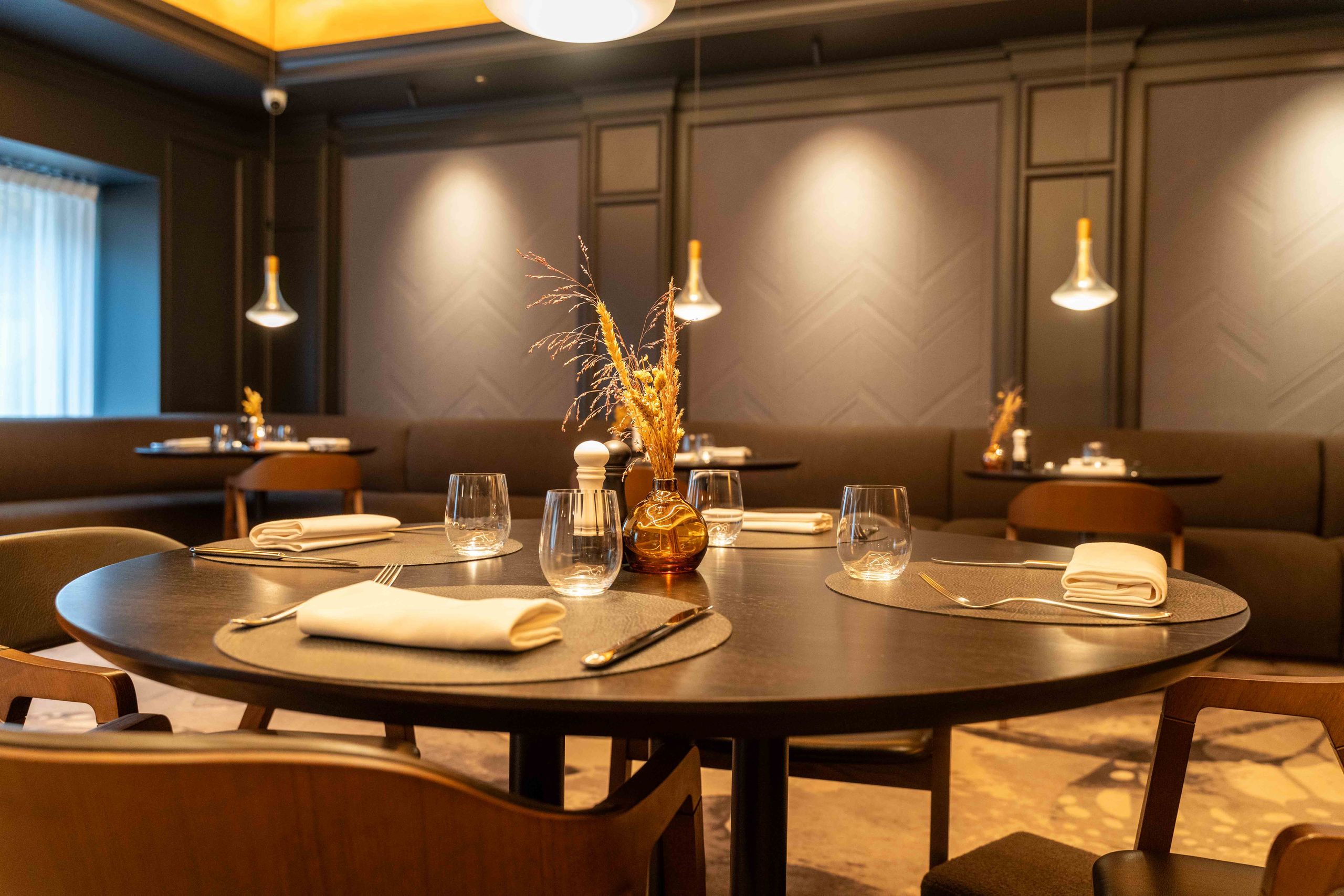 Une table à manger bien dressée dans un restaurant avec des chaises et un éclairage doux.