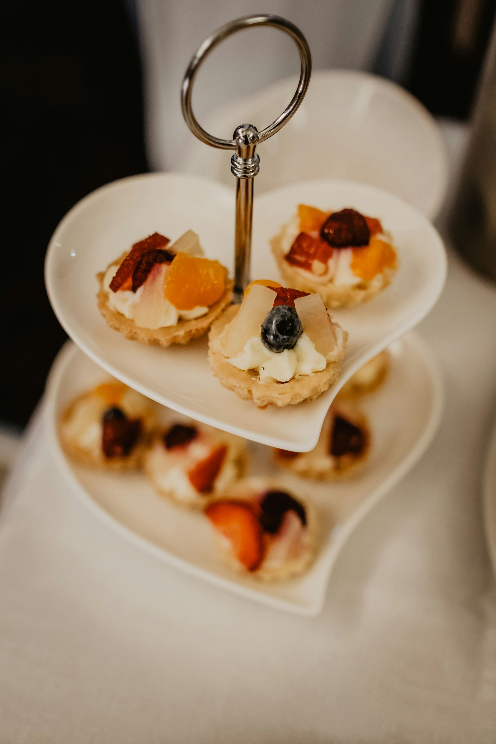A two-tiered serving tray with small fruit tarts.